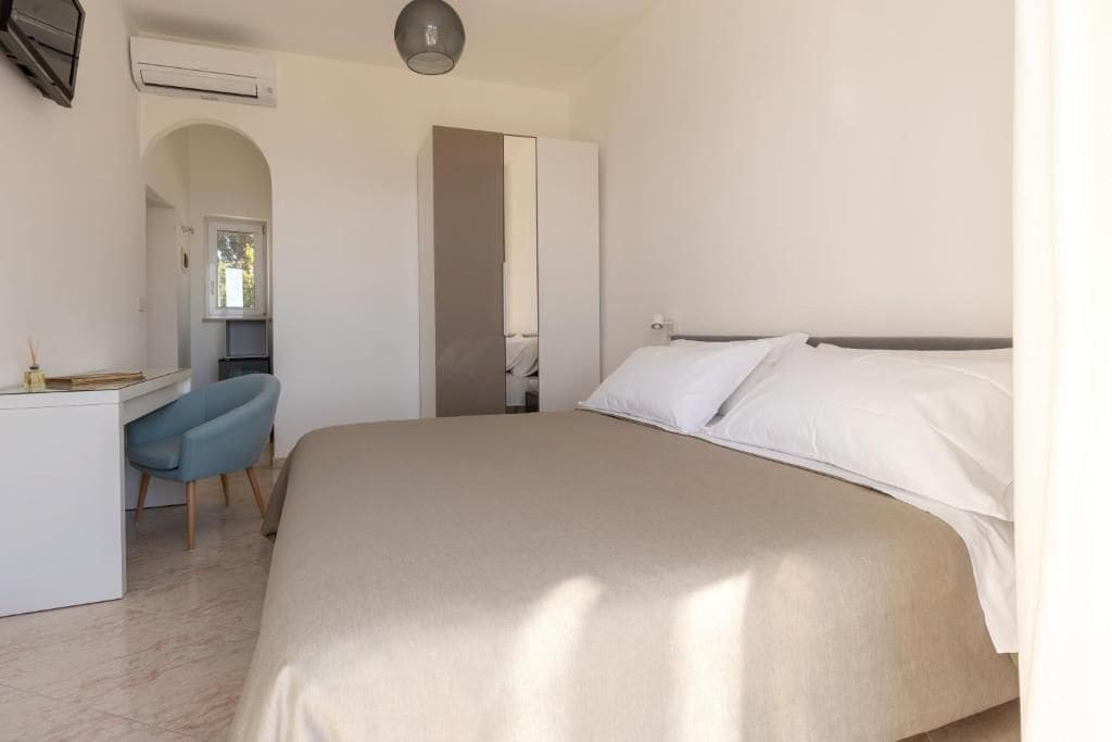 A bedroom with a bed, a desk, and a chair.