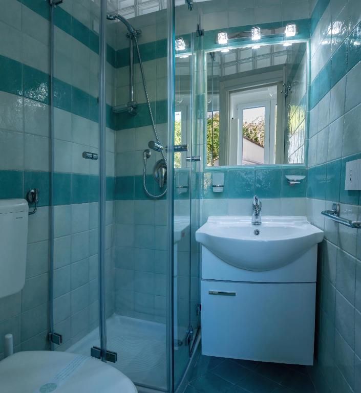 Une salle de bain avec une douche à parois de verre, un lavabo blanc et un miroir au-dessus.