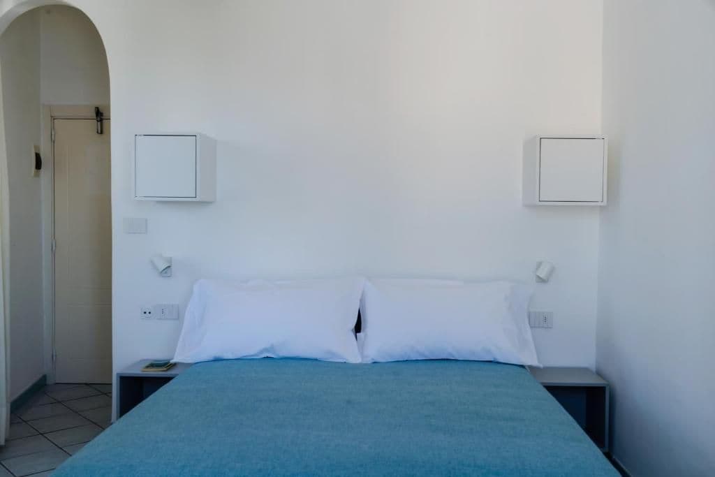 A room with a bed, two bedside tables, and a door.