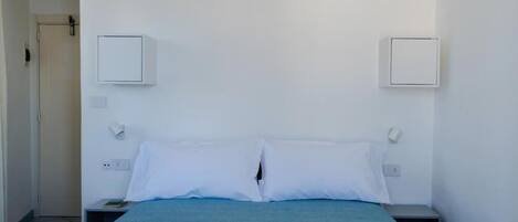 A room with a bed, two bedside tables, and a door.