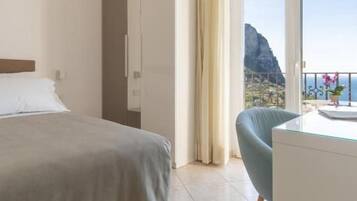 A hotel room with a bed, a desk, a chair, and a large window with curtains.
