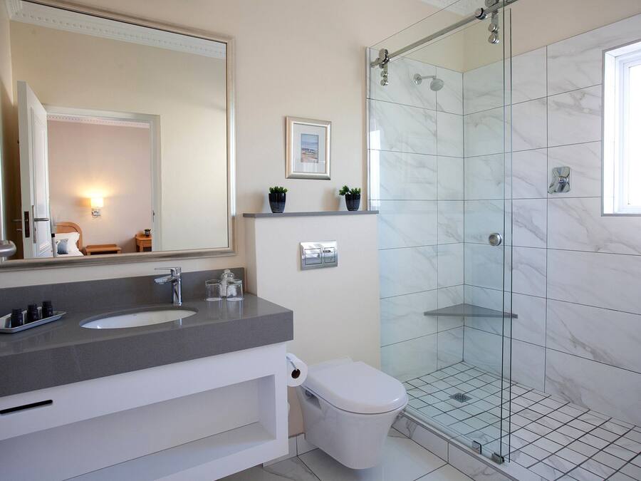 Un baño moderno con ducha de vidrio, tocador con doble lavabo y un inodoro.