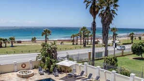 Une piscine sur le toit, avec des chaises longues, des palmiers et une vue sur la plage et l’océan.