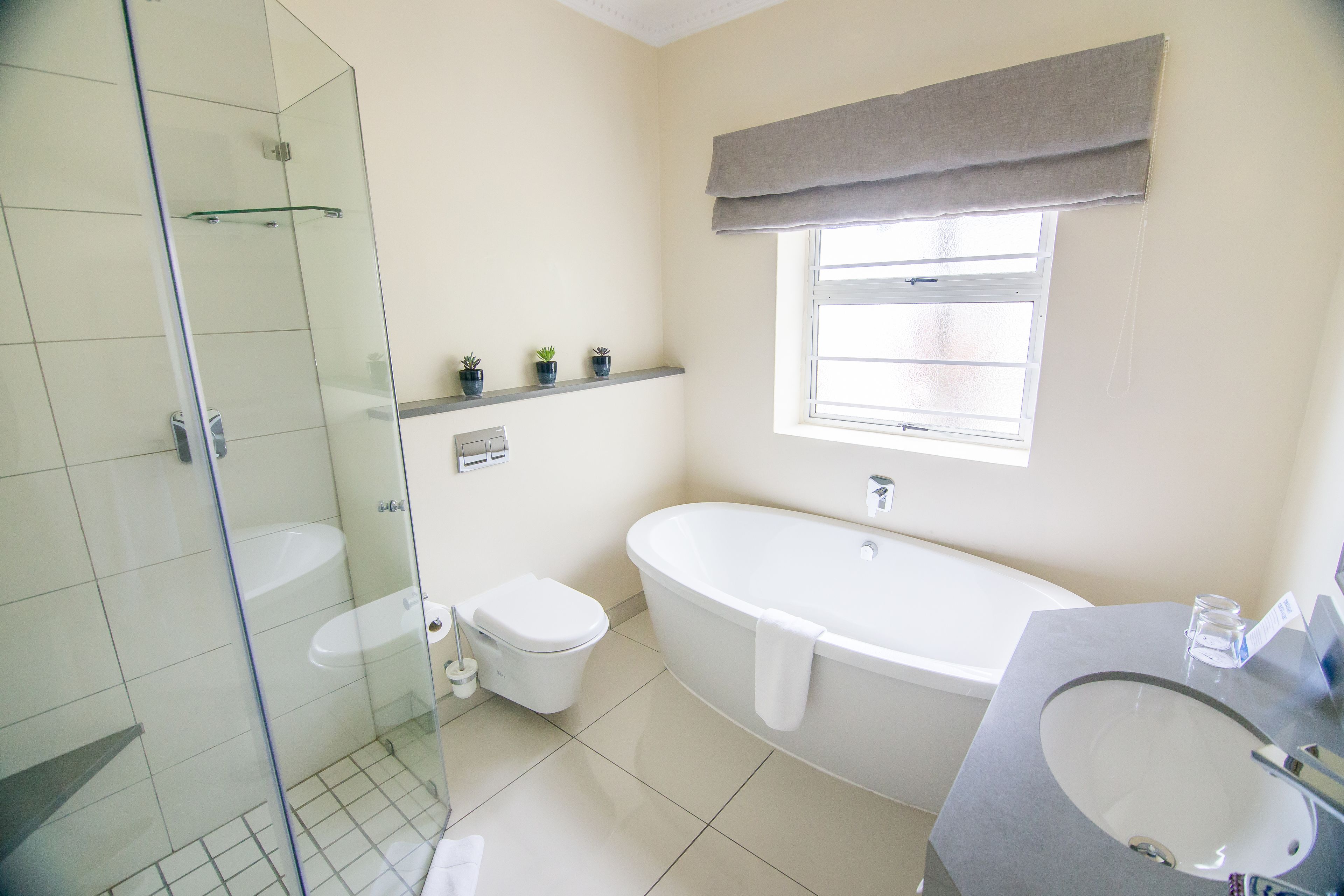A modern bathroom with a glass shower enclosure, a freestanding bathtub, a toilet, and a vanity with a sink.