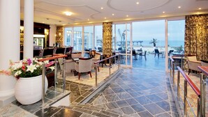 Un hall d’hôtel doté d’un bar, d’un espace salon et offrant une vue sur la plage.