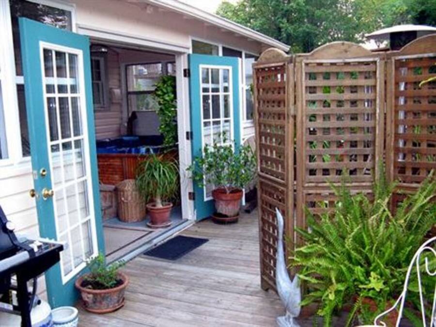 A wooden deck with potted plants, a blue door, and a wooden fence.