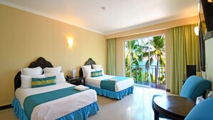 Une chambre d’hôtel avec deux lits, un coin repas et une vue sur les palmiers.