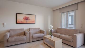 A living room with two beige sofas, a wooden coffee table, and a painting of a tree on the wall.