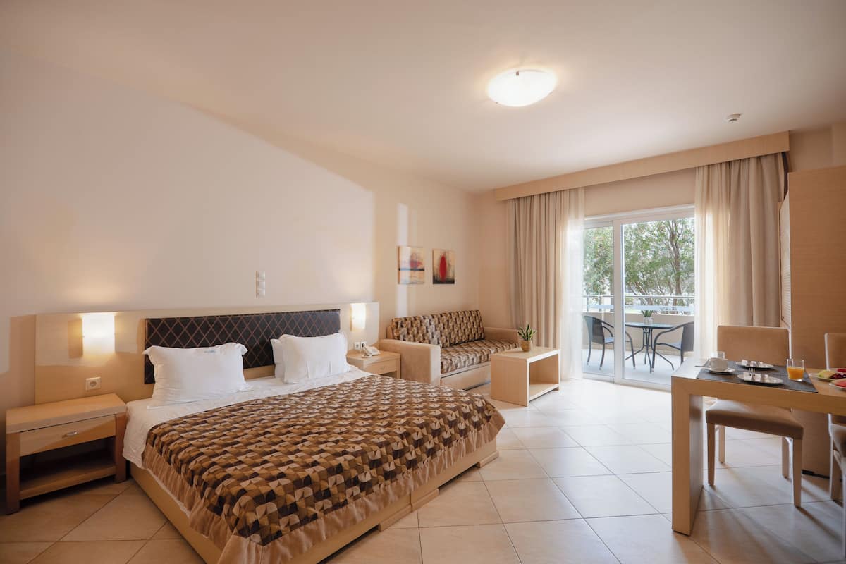 Une chambre d’hôtel dotée d’un grand lit, de tables de chevet, d’un bureau et d’un coin repas offrant une vue sur l’extérieur.