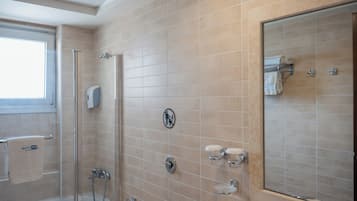 Un baño moderno con cabina de ducha de vidrio, lavabo con espejo e inodoro.