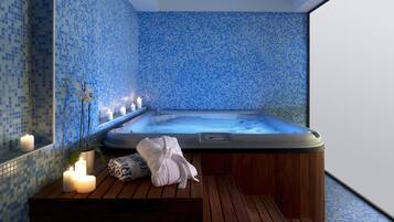 Relax in a serene spa room with a large hot tub and a calming mosaic tile wall.