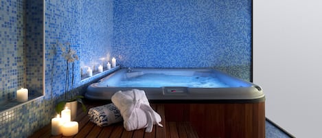 Une salle de spa équipée d’un bain à remous, d’un banc en bois, de bougies et d’un mur carrelé.