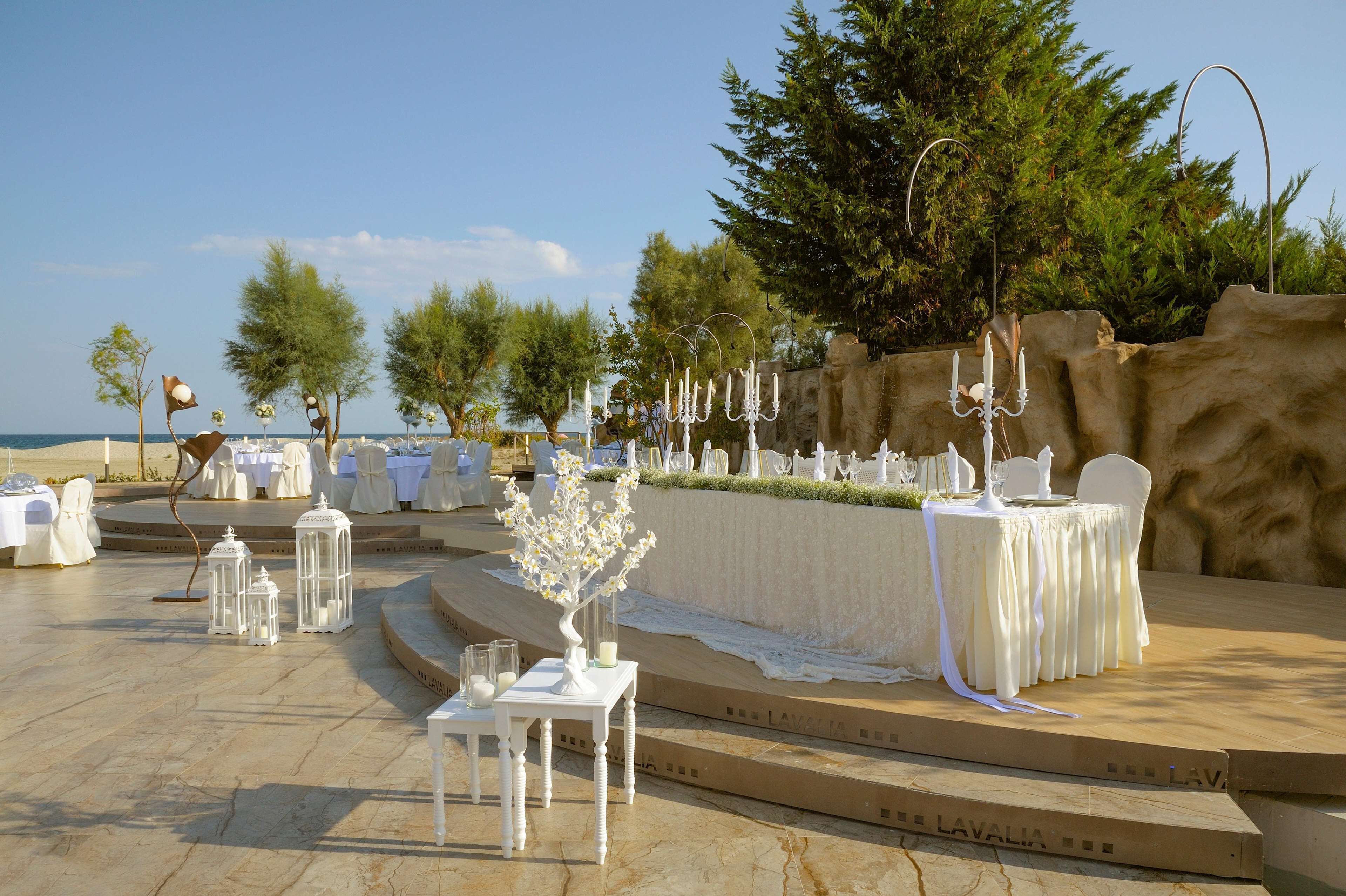 An outdoor wedding setup with tables, chairs, and decorative elements like candles and lanterns.