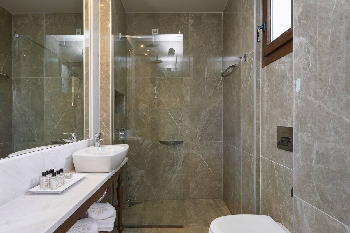 A modern bathroom with a glass-enclosed shower, a vanity with a sink, and a toilet.