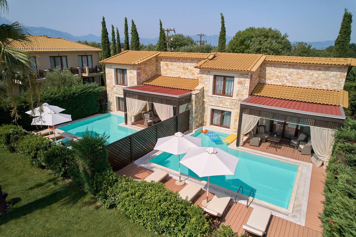A pool area with two separate pools, lounge chairs, and umbrellas.