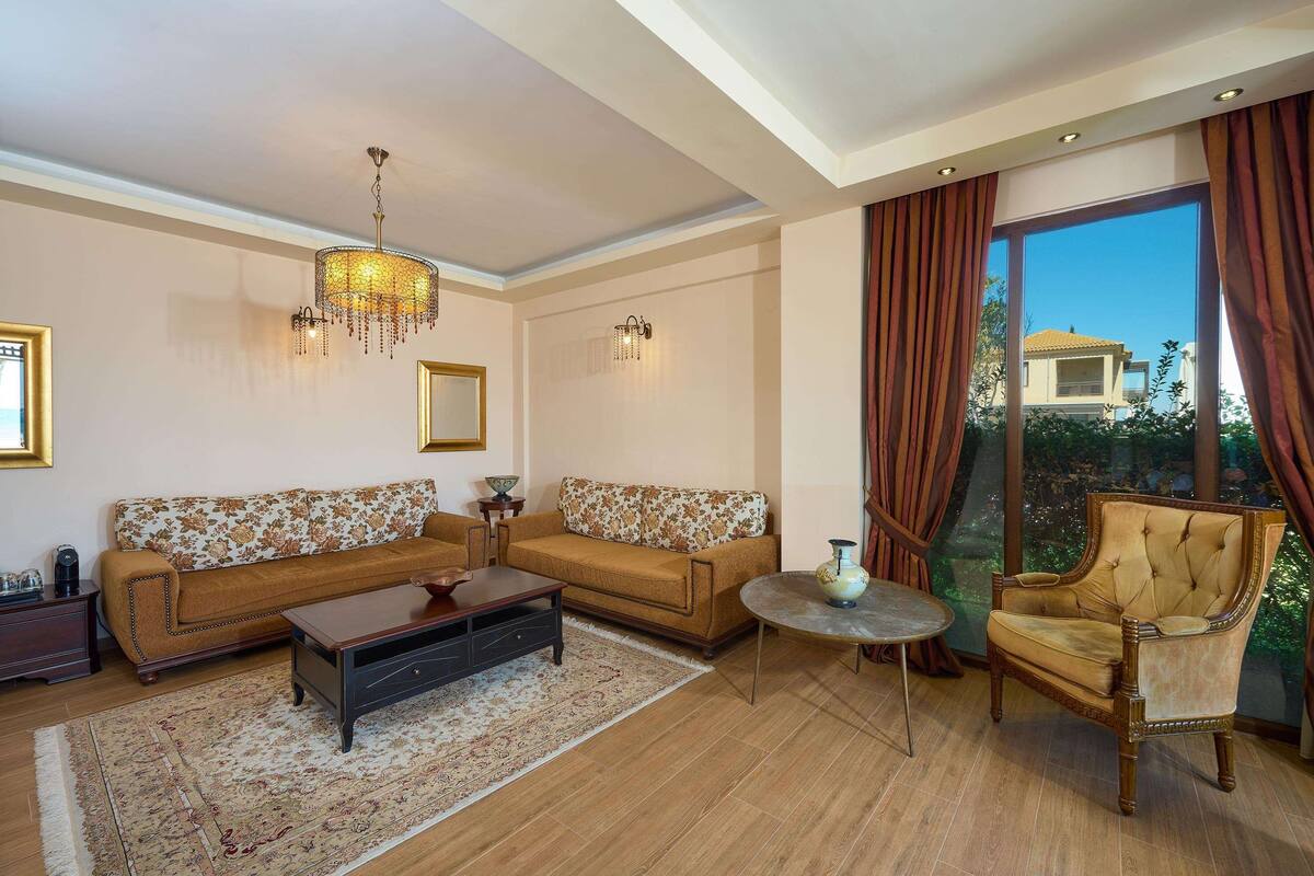A living room with a sofa set, a coffee table, a chair, and a chandelier.