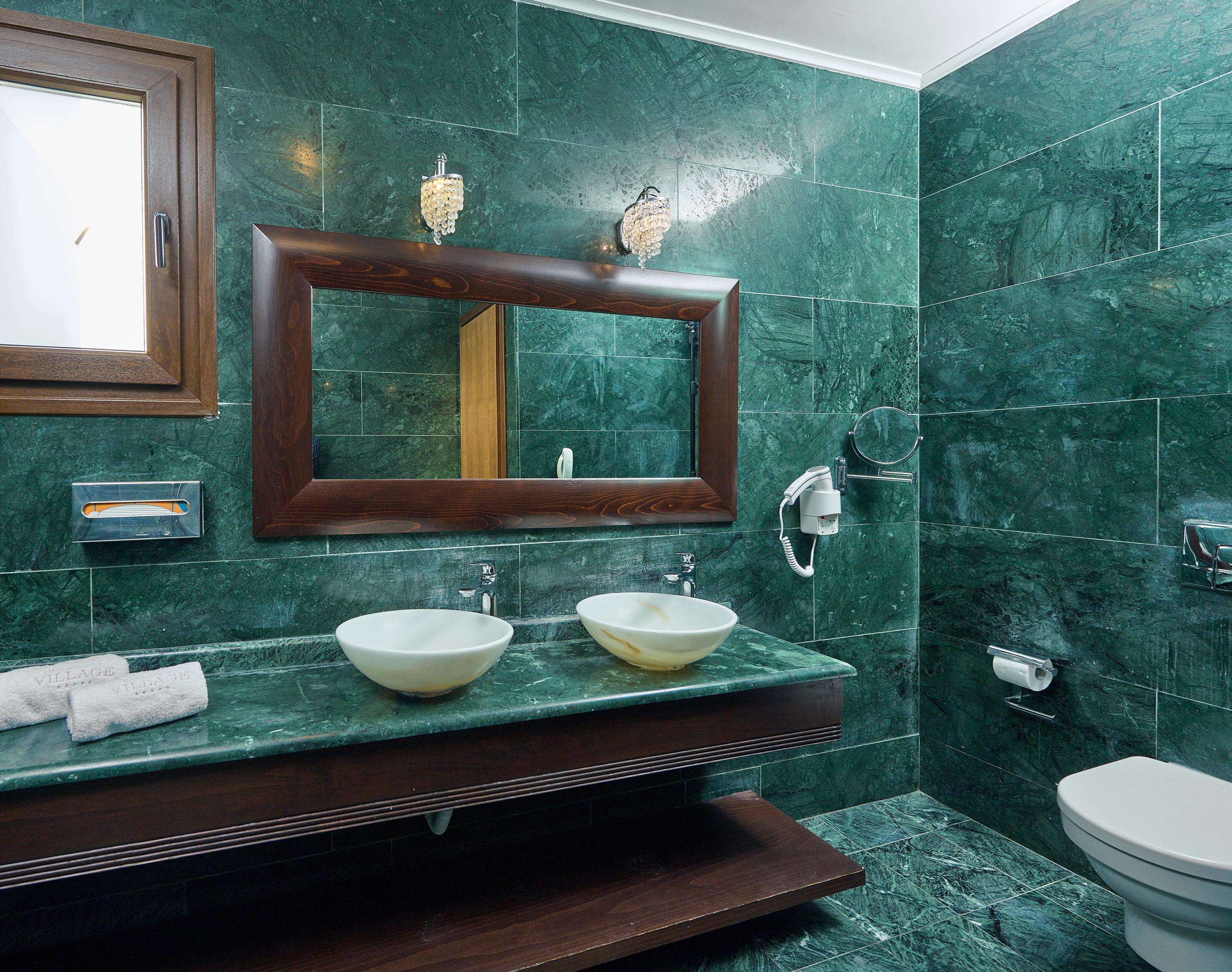 A bathroom with two sinks, a mirror, a towel rack, and a toilet.