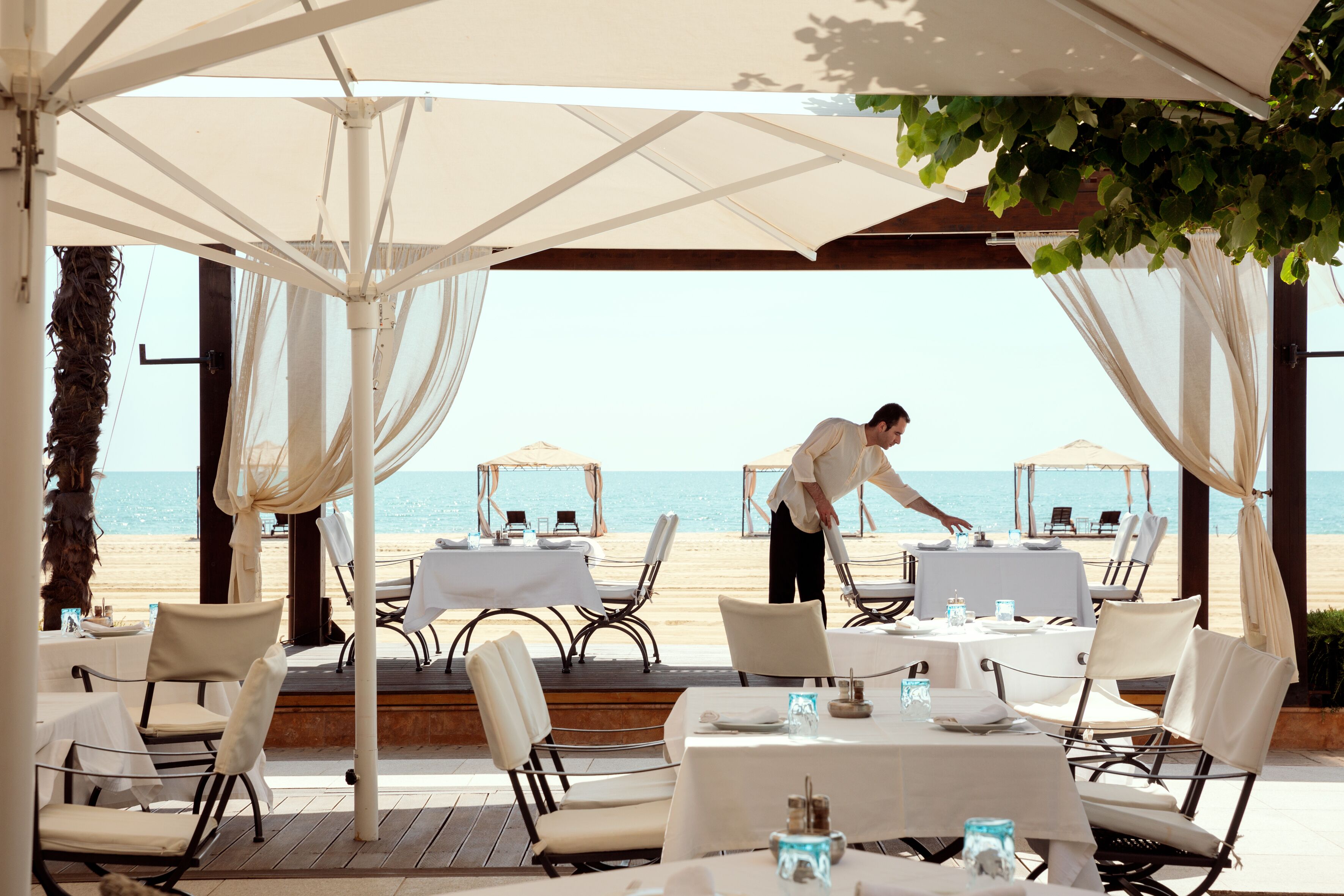 Un espace extérieur aménagé pour les repas, avec des tables et des chaises, offrant une vue sur la plage.
