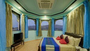 Un dormitorio con una cama, un televisor y un teléfono sobre una mesita de noche.