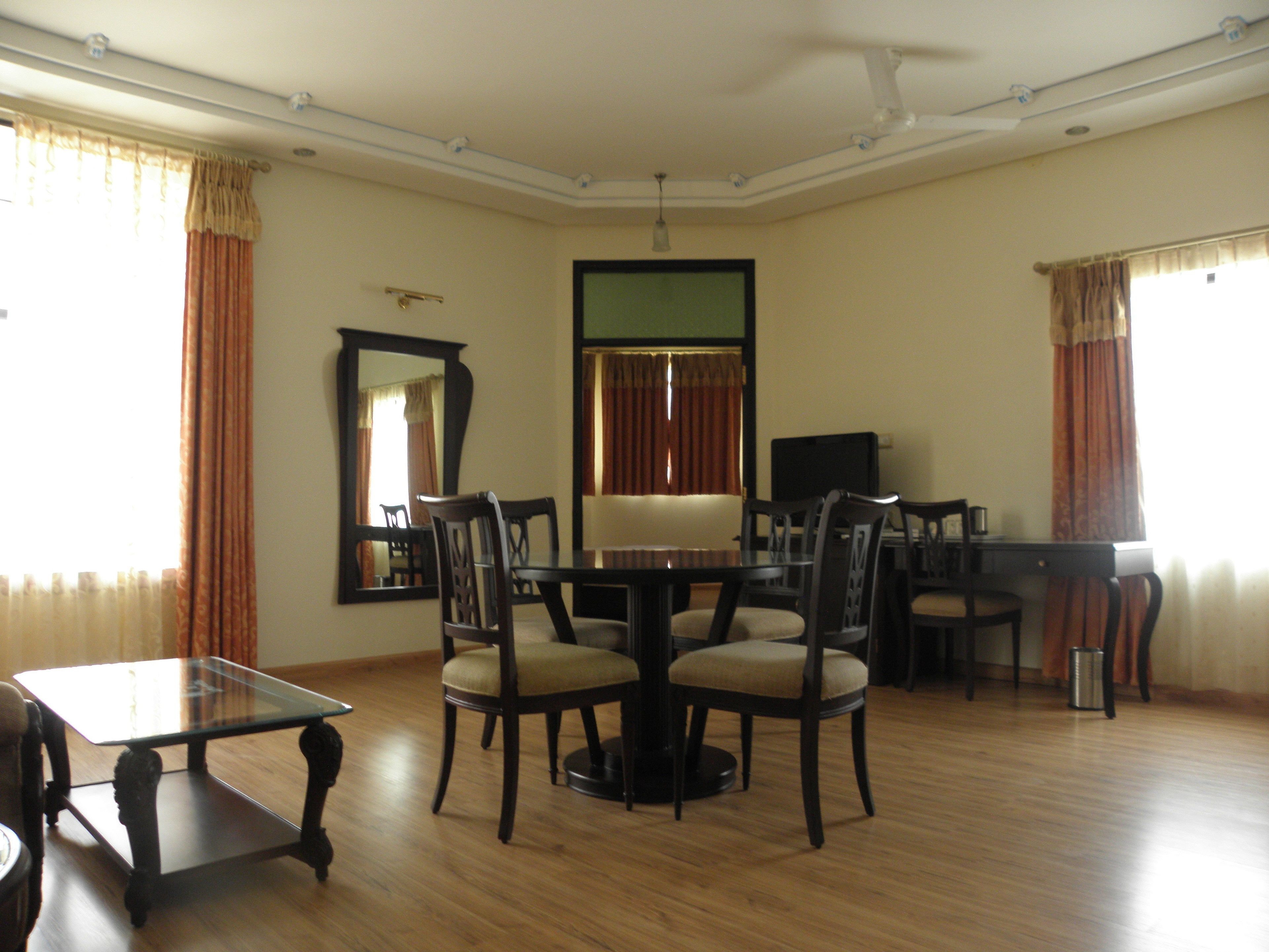 A dining area with a round table, chairs, a television, and a large mirror.
