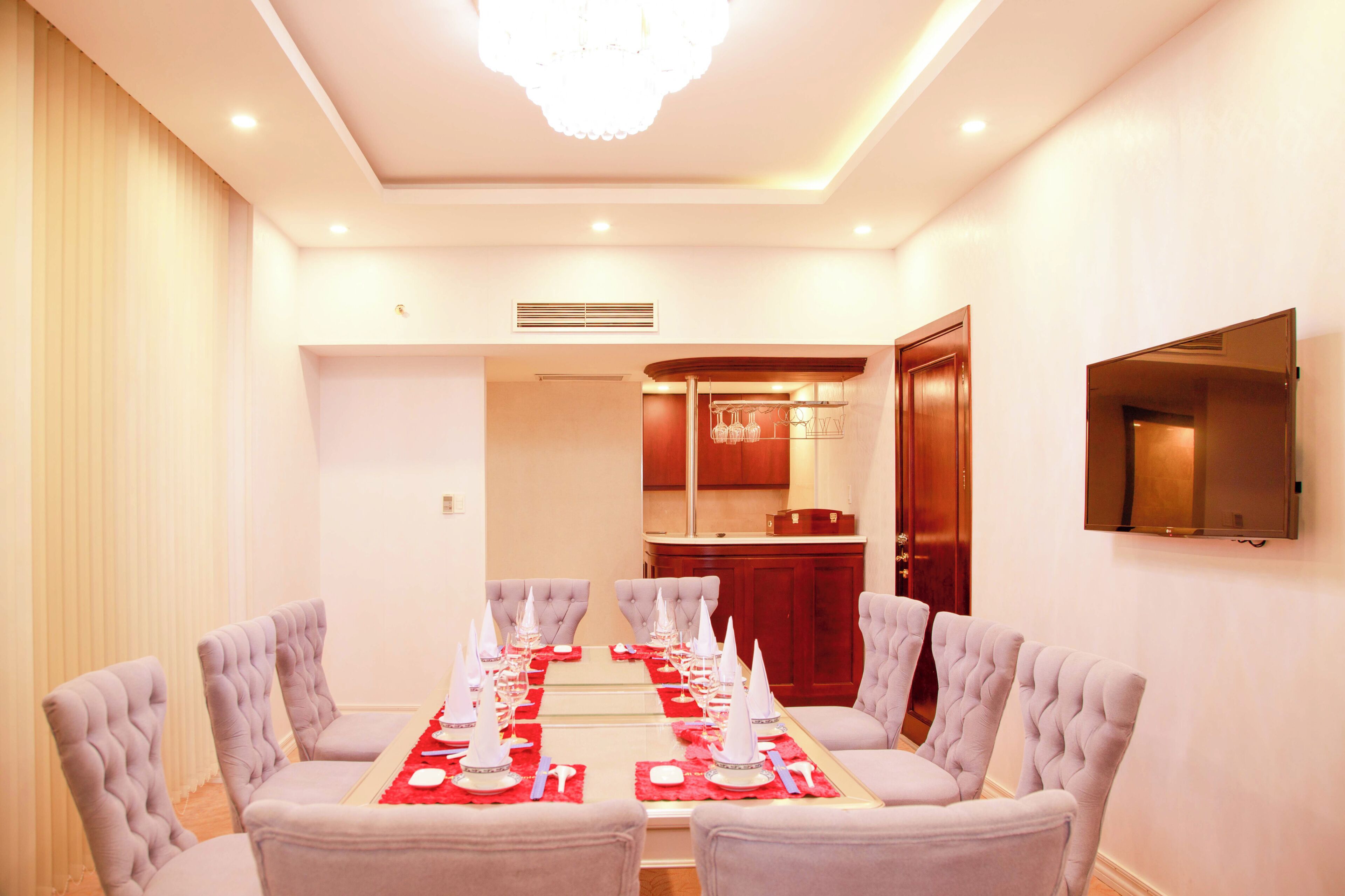 A conference room with a long table set for a meeting, surrounded by chairs, and a television mounted on the wall.