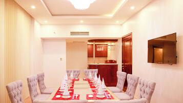 A conference room with a long table set for a meeting, surrounded by chairs, and a television mounted on the wall.
