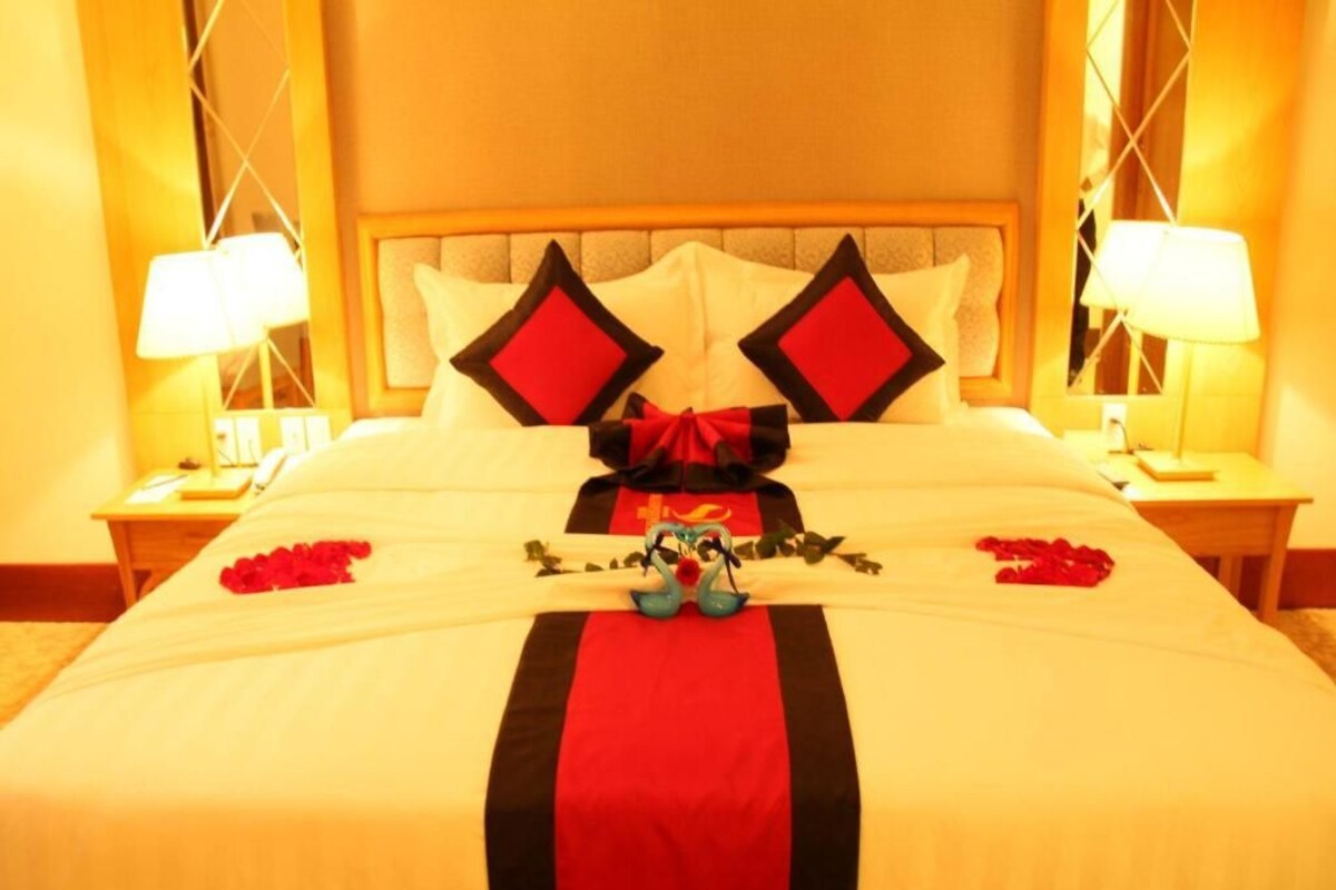 A hotel room with a large bed, two bedside tables with lamps, and a decorative bow on the bed.
