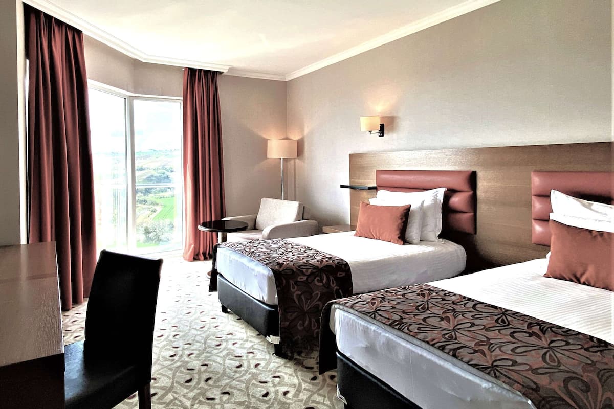 A hotel room with two beds, a desk, and a chair.