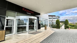 A modern hotel entrance with a glass facade, a revolving door, and a clear sky view. - Ramada by Wyndham Tekirdag (Tekirdag)