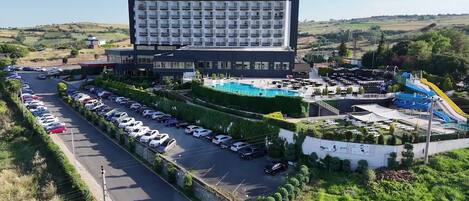 Un hotel con un edificio grande, piscina y estacionamiento.