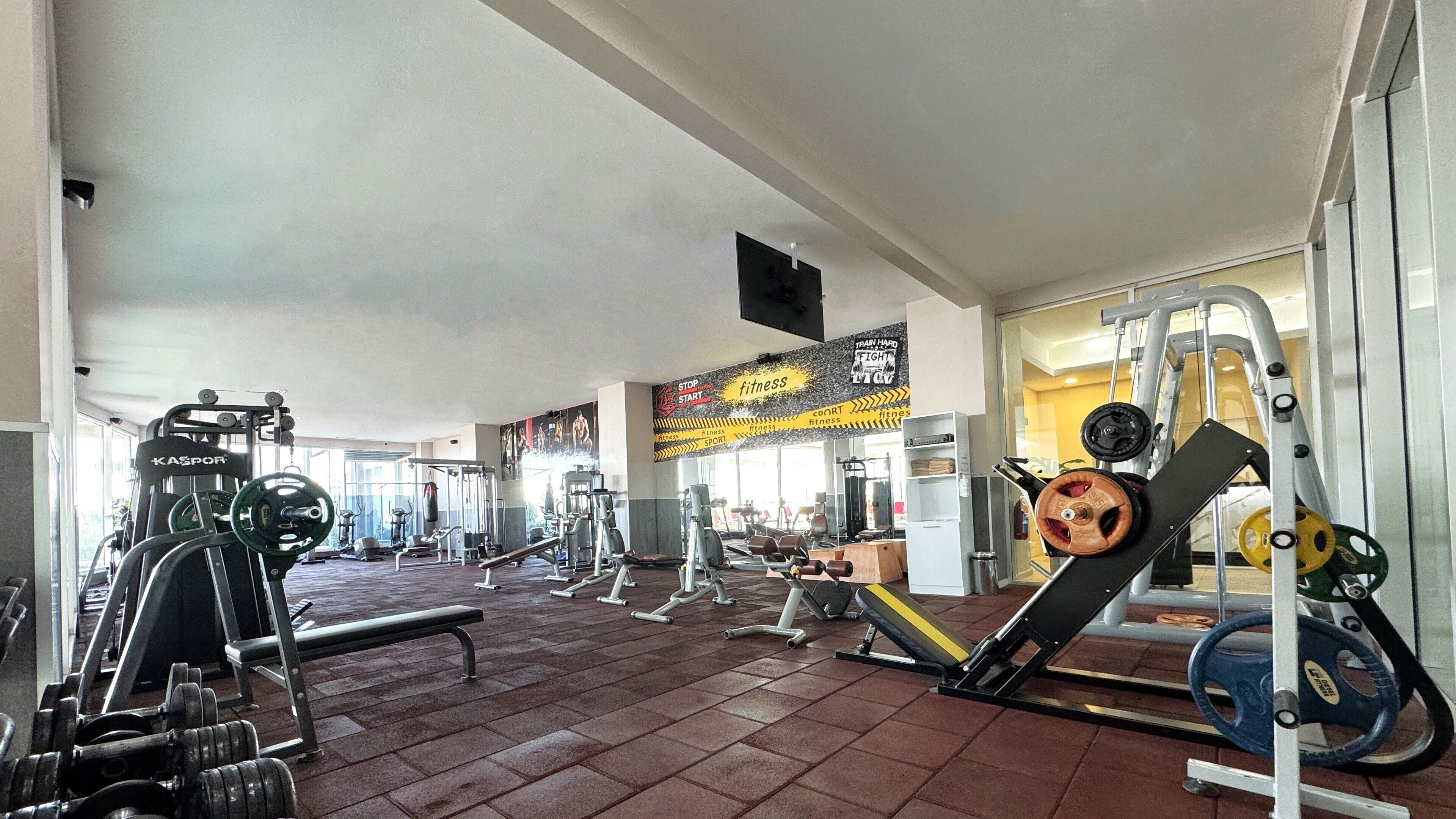 A gym with various exercise equipment, including weight machines, benches, and free weights.