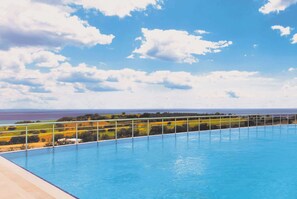 A swimming pool with a view of the ocean and a clear sky.