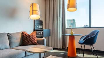 A modern living room with a grey sofa, a round coffee table, a blue chair, and two pendant lights.