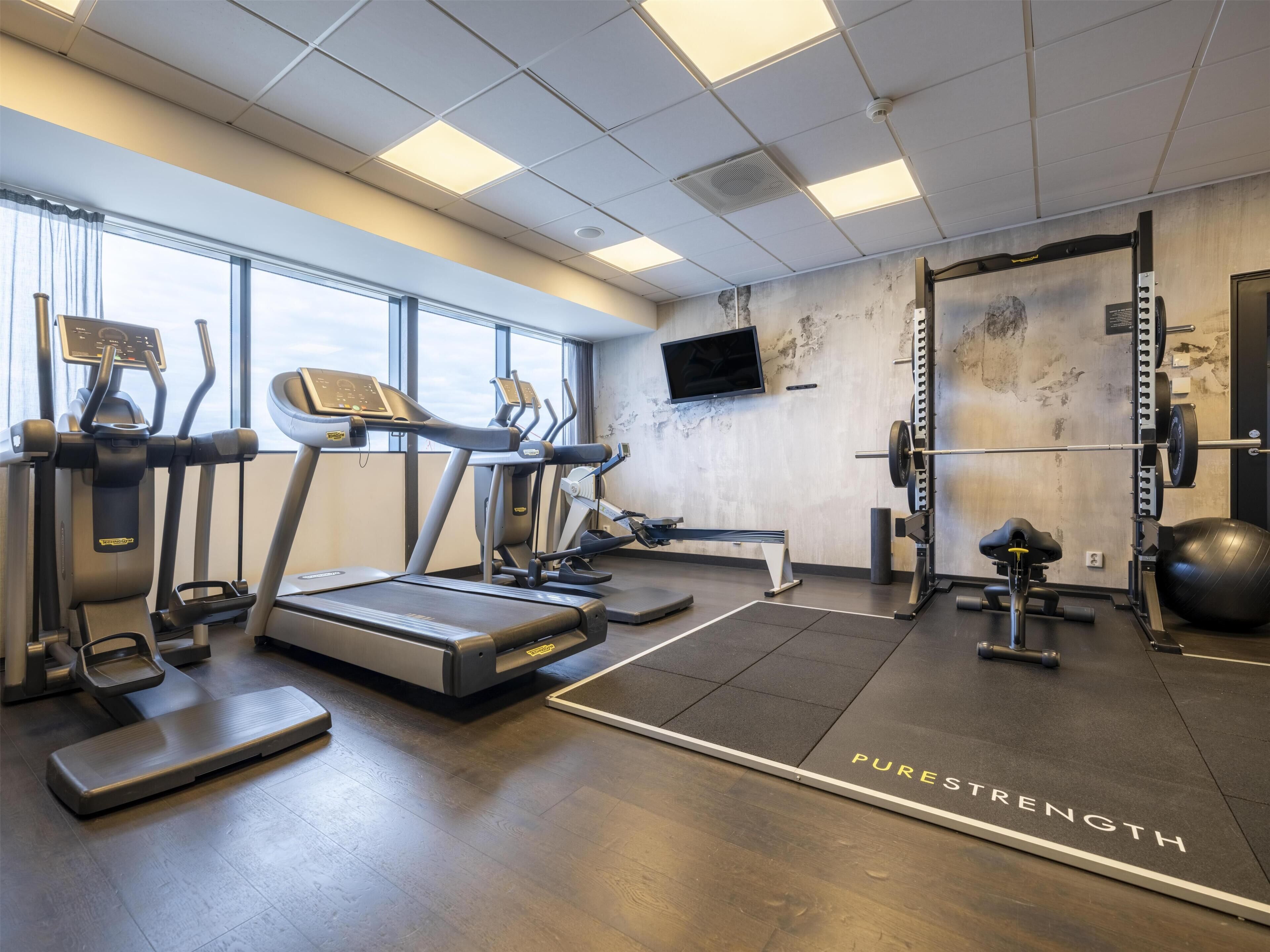 A gym with treadmills, a rowing machine, a bench press, and a squat rack.