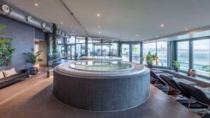 A modern indoor pool area with a hot tub, seating, and large windows offering city views. - Radisson Blu Riverside Hotel, Gothenburg (Gothenburg)