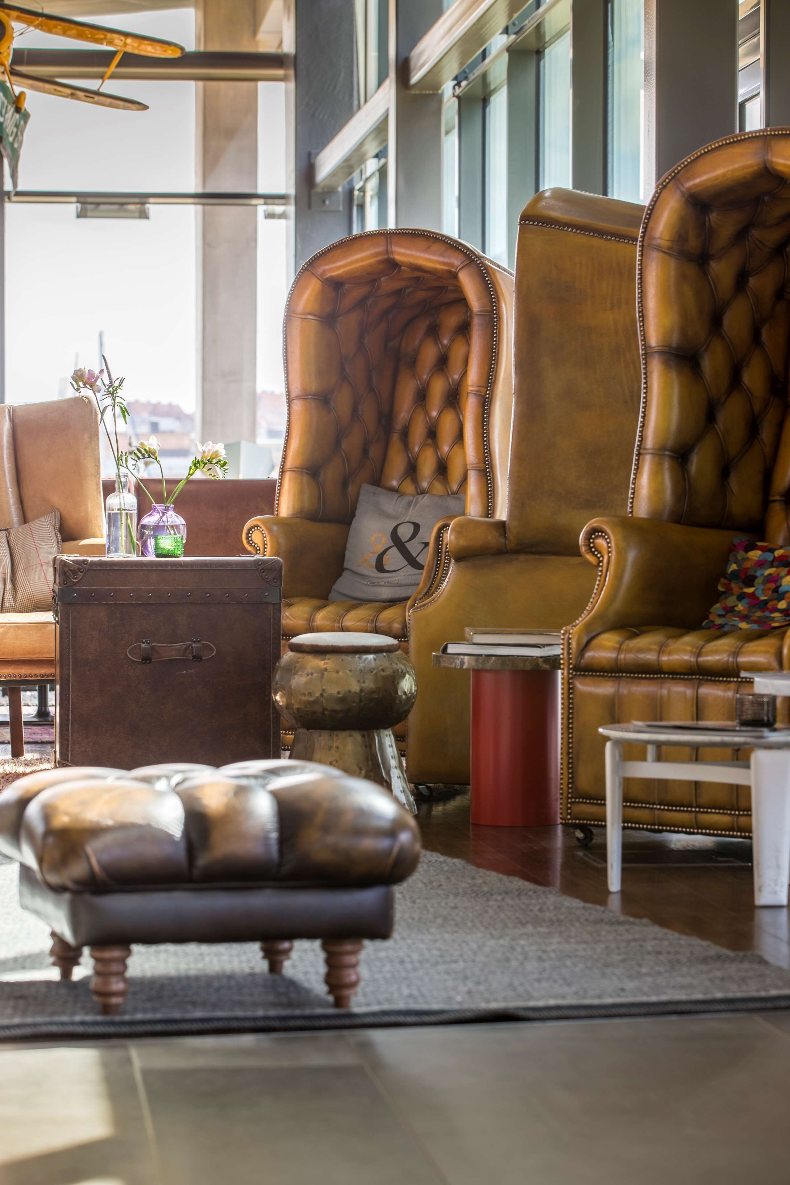 Uma sala de estar moderna com poltronas de couro, uma mala vintage e uma pequena mesa.