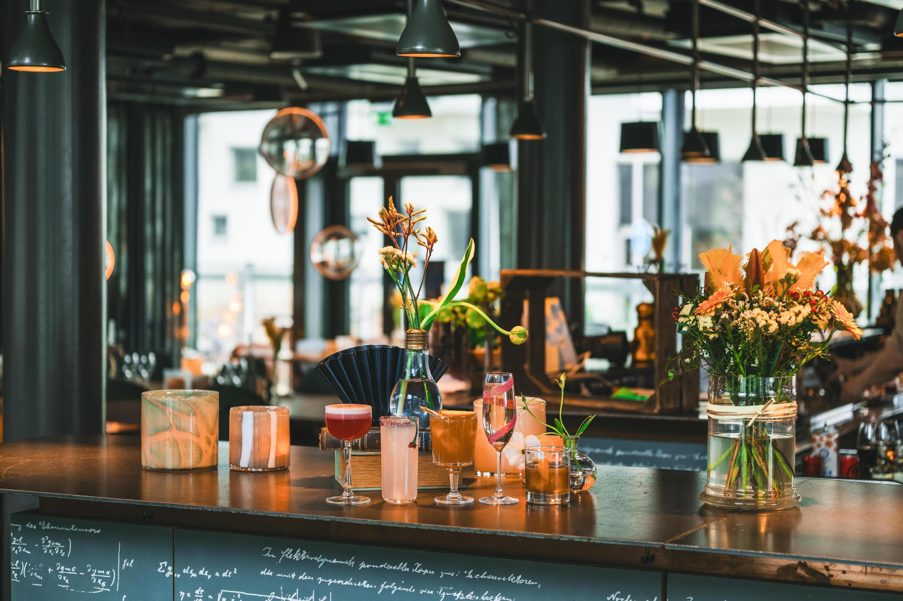 Zona de bar amb diverses begudes, un ram de flors i un menú a la pissarra.