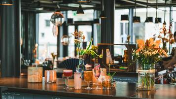 A bar area with various drinks, a vase with flowers, and a chalkboard menu.