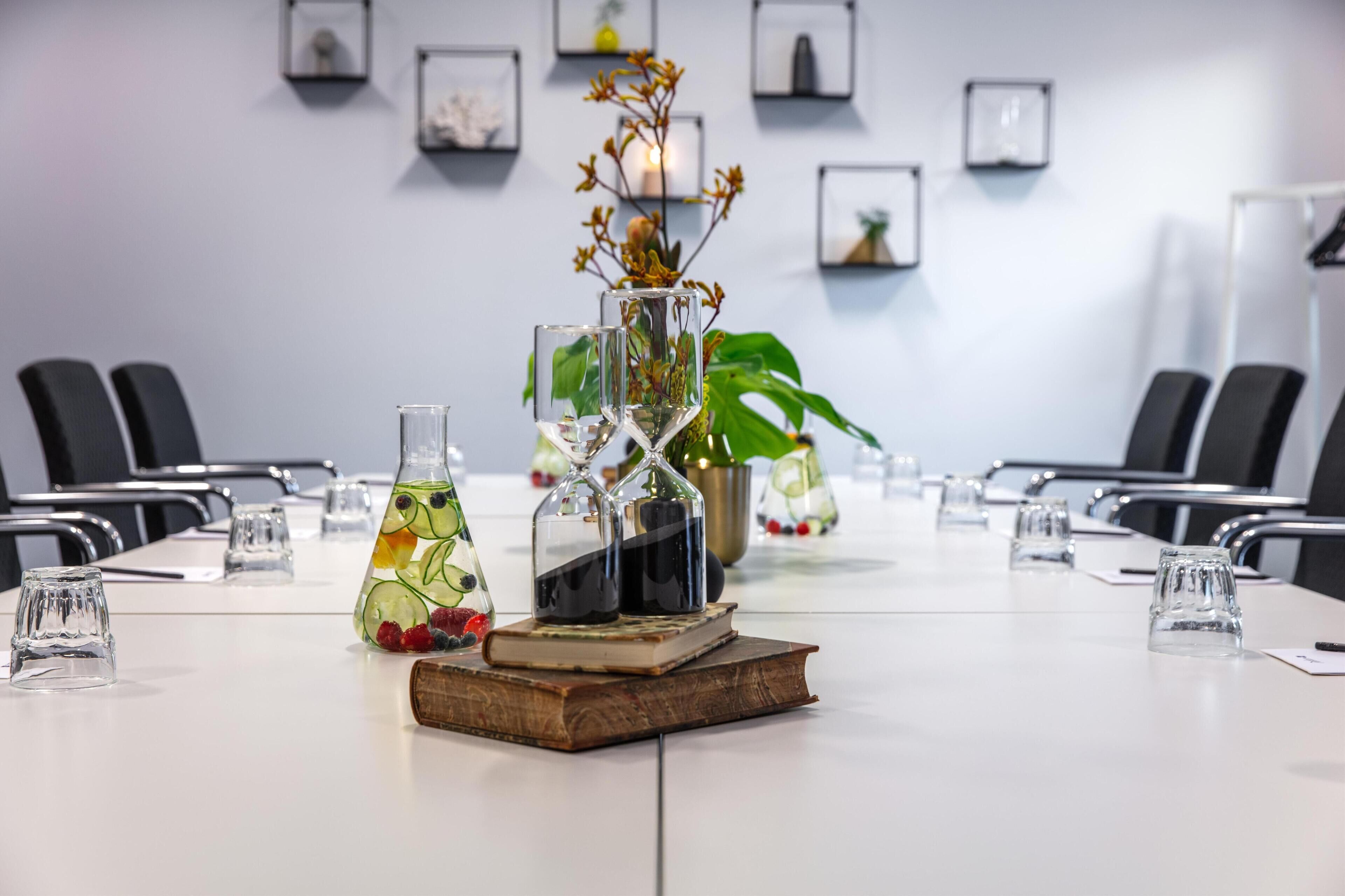 A conference room with a long table, chairs, a decorative centerpiece, and framed pictures on the wall.
