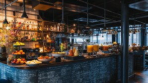 A bar area with a chalkboard menu, shelves with bottles, and a variety of fruits and condiments.
