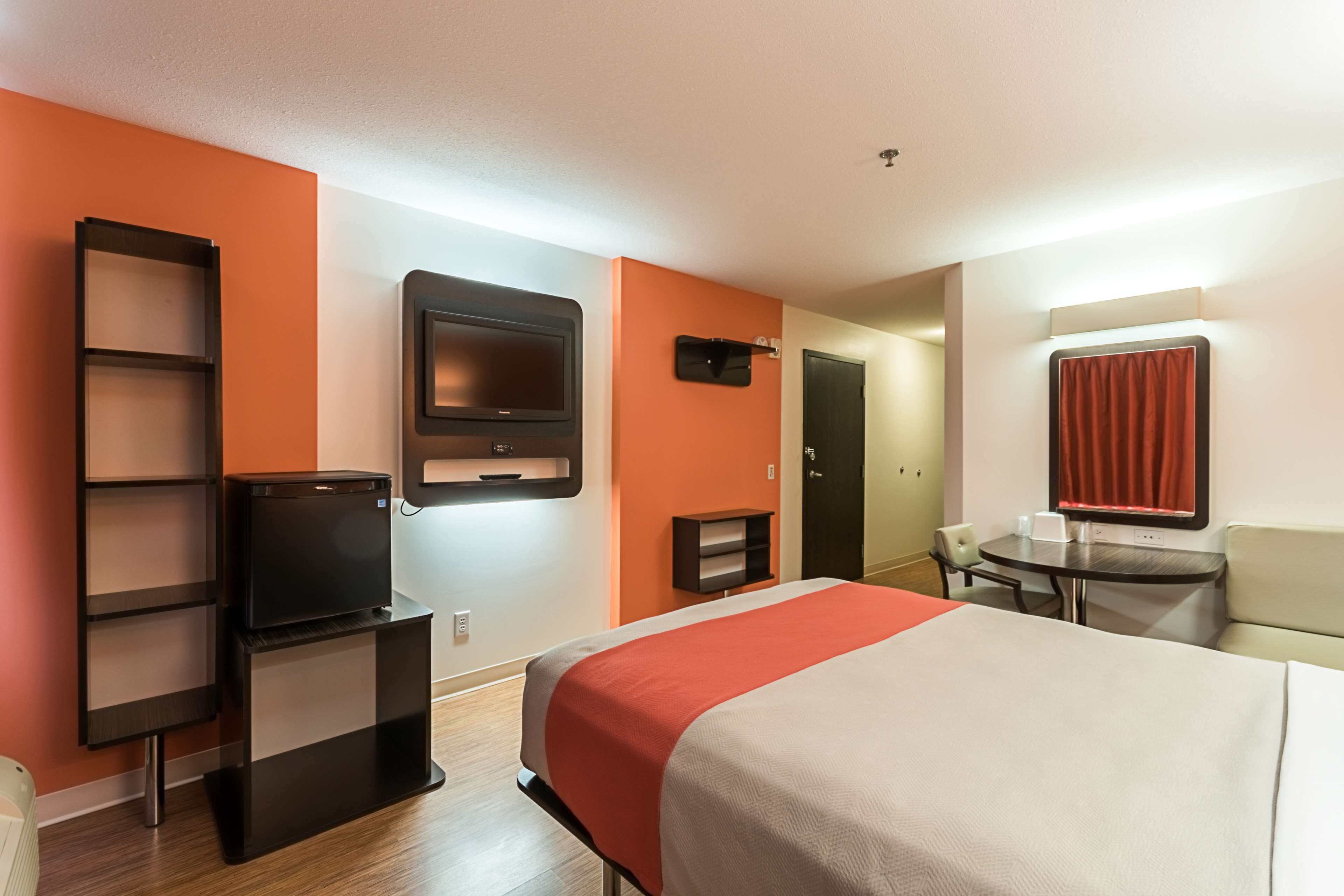 Une chambre d’hôtel avec un lit, une télévision, un bureau et une chaise.
