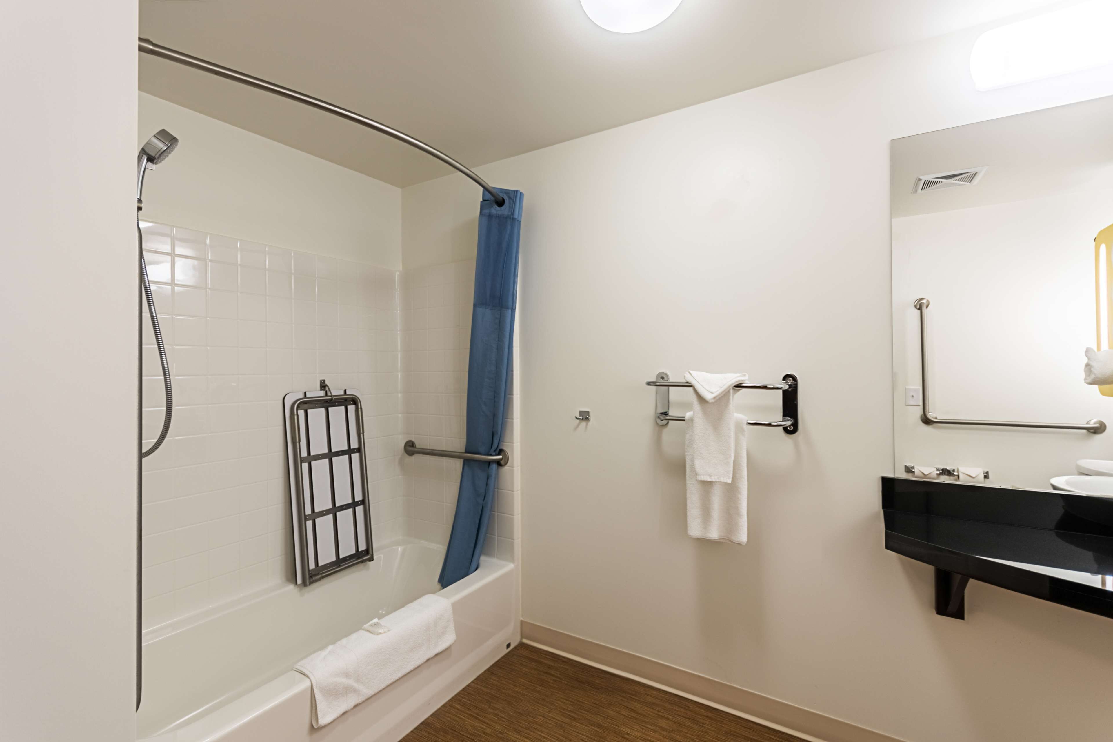 Une salle de bain moderne avec une baignoire, une douche et un lavabo noir agrémenté d’un miroir.