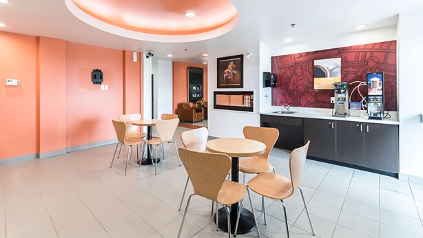 Un interior moderno con mesas y sillas redondas, una zona de cocina con electrodomésticos y obras de arte en las paredes.