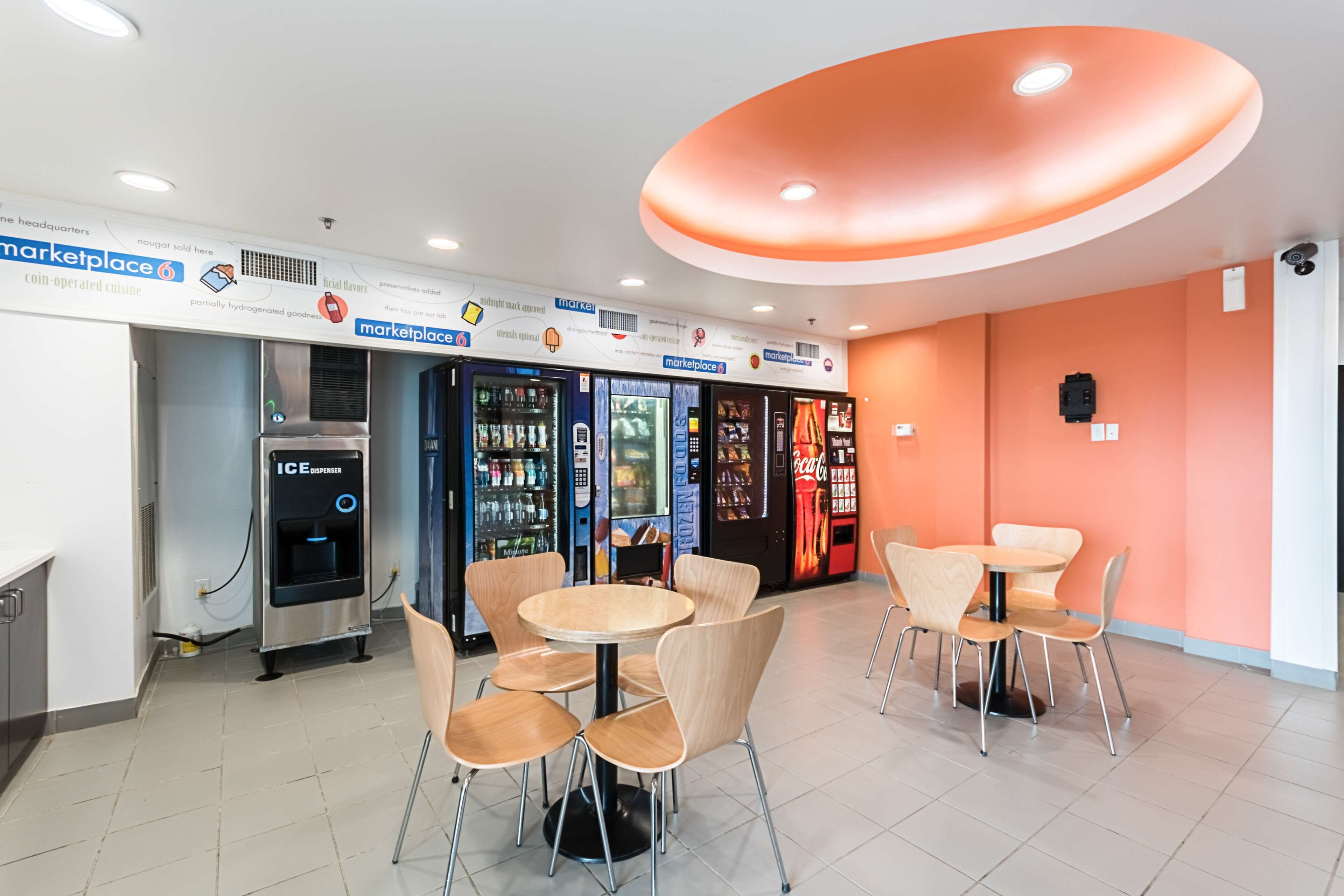 Un espacio interior moderno con zonas de estar, máquinas expendedoras y dispensador de hielo.