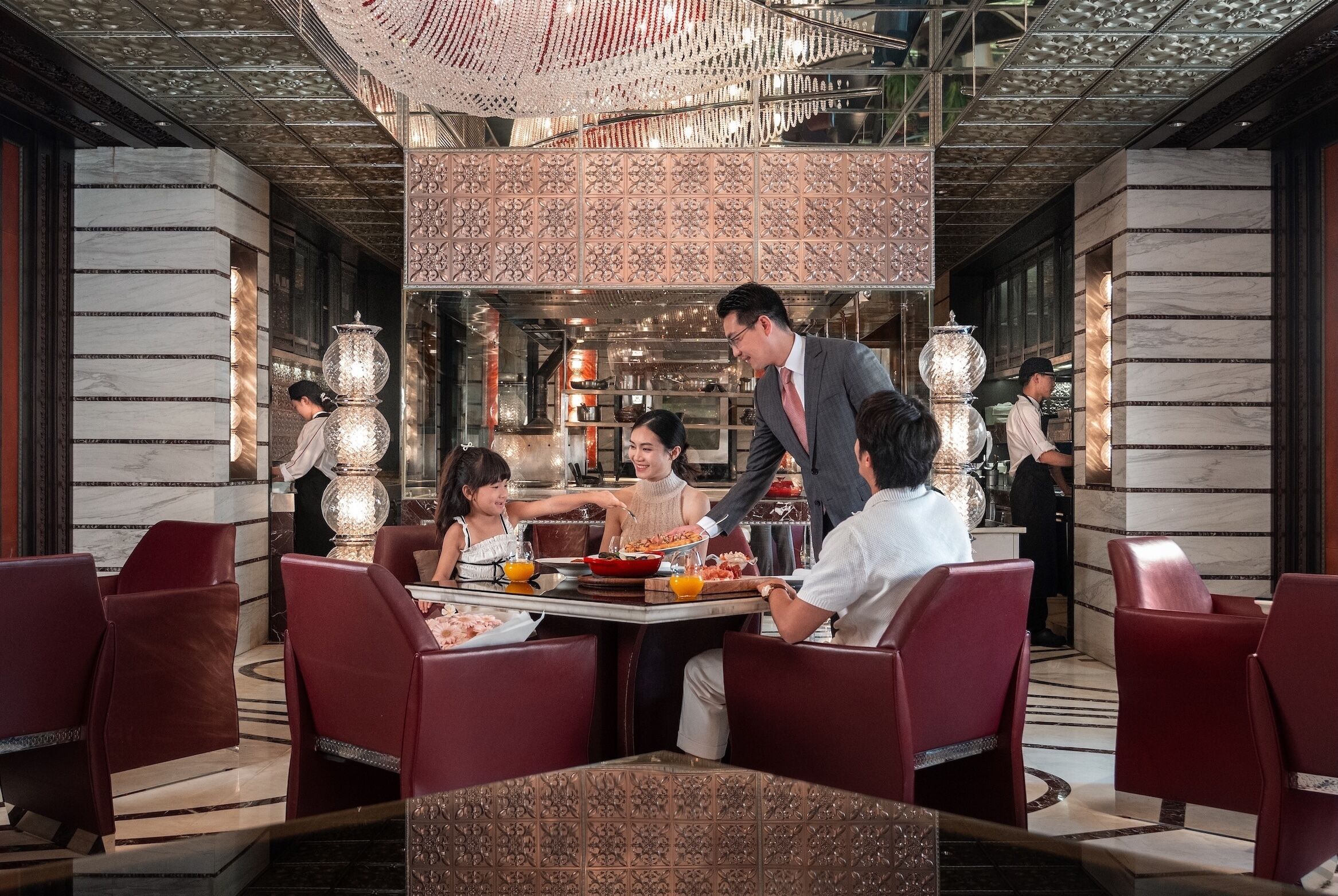 A formal dining area with marble walls, red upholstered chairs, and a central serving station.