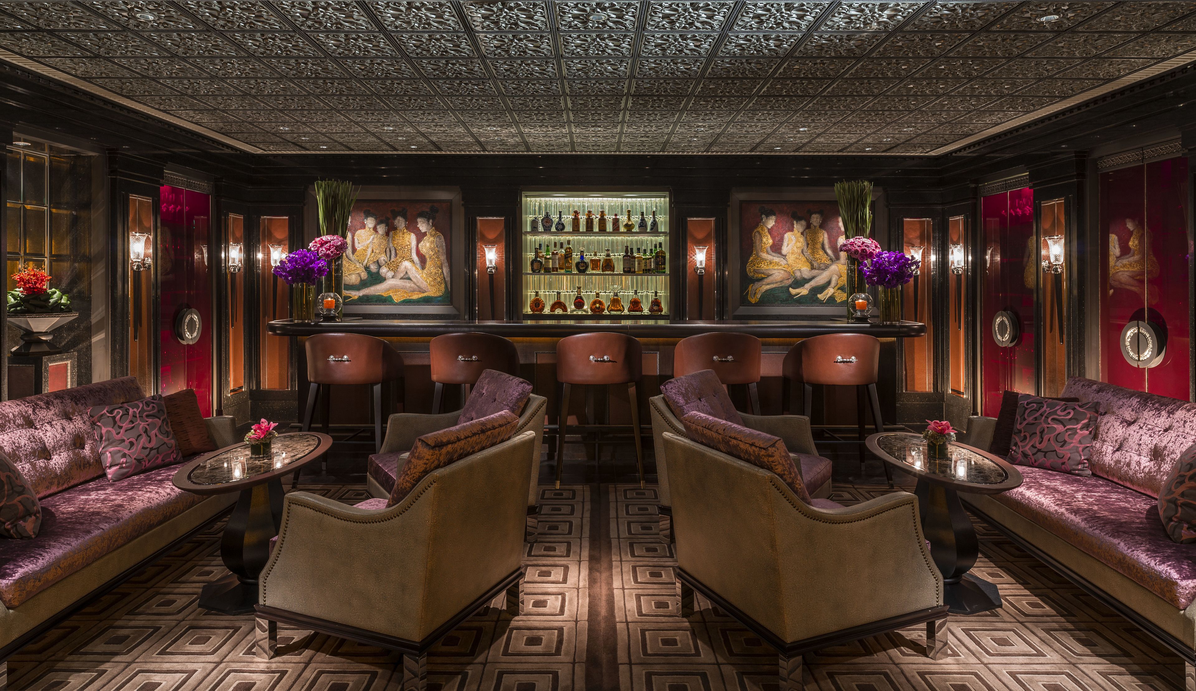 Un espace bar avec un sol à motifs, des tabourets de bar et des canapés.
