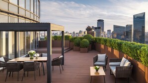 A rooftop terrace with a wooden deck, seating area, and a view of the city skyline. - Four Seasons Hotel Beijing (Beijing)