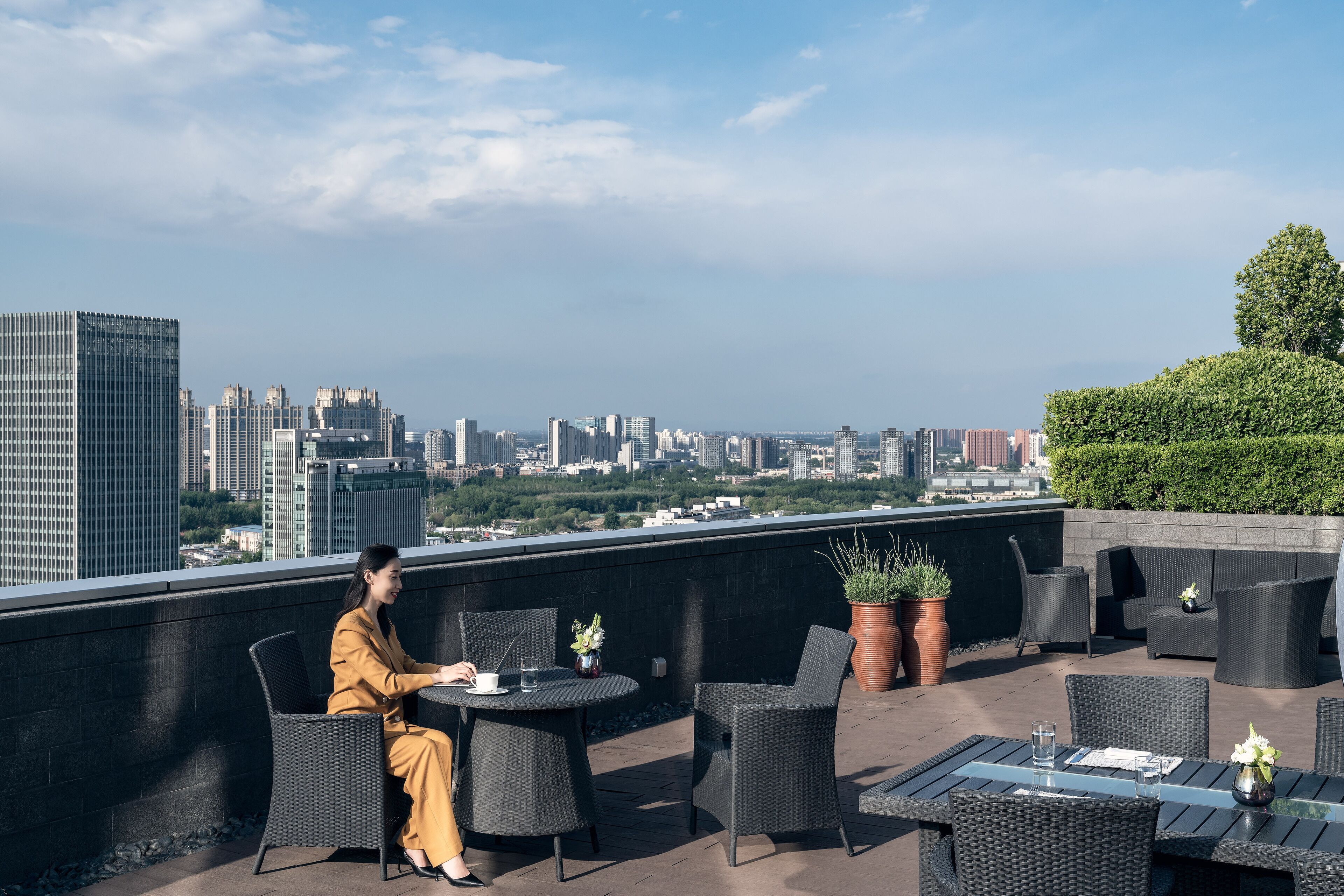 A rooftop terrace with outdoor seating, a city view, and a potted plant.