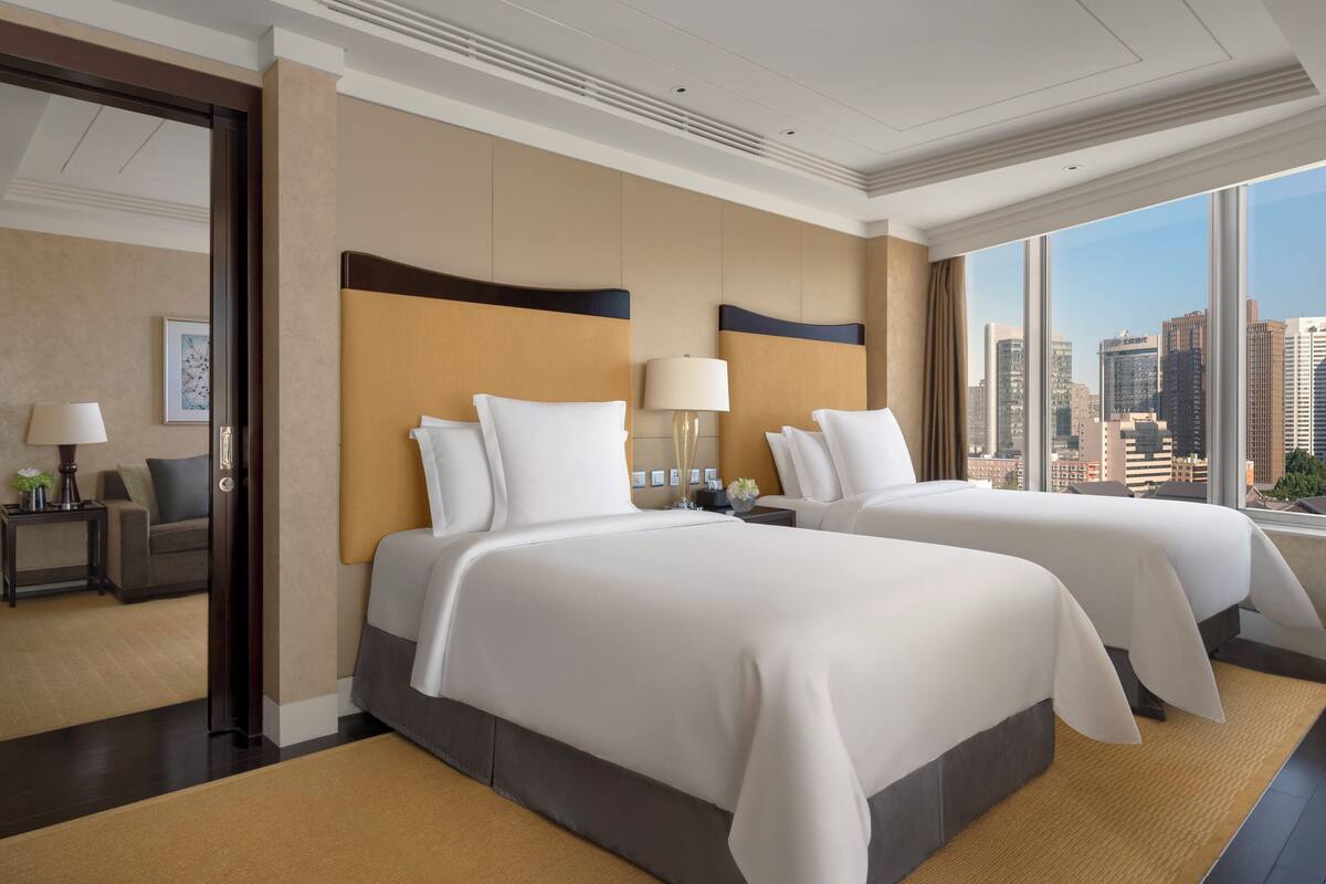 A hotel room with two beds, a city view, and a modern design.