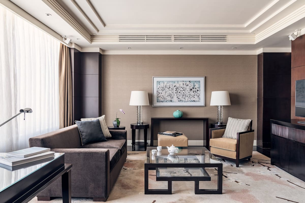 A modern living room with a sofa, armchairs, a coffee table, and a fireplace.